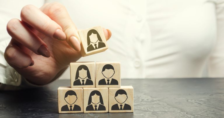 Business woman puts a wooden cube with the image of workers. Mixed staff concept. Personnel management in a team. Human resources. Dismissal employee. Hiring Headhunting. Choosing a person from a team